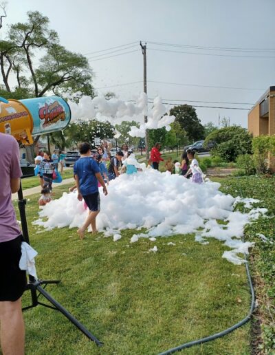 Summer reading 2025 kick-off party kids playing outside the library with foam.