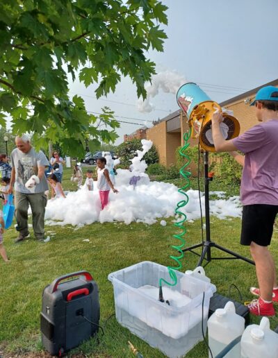Summer reading 2025 kick-off party kids playing outside the library with foam.