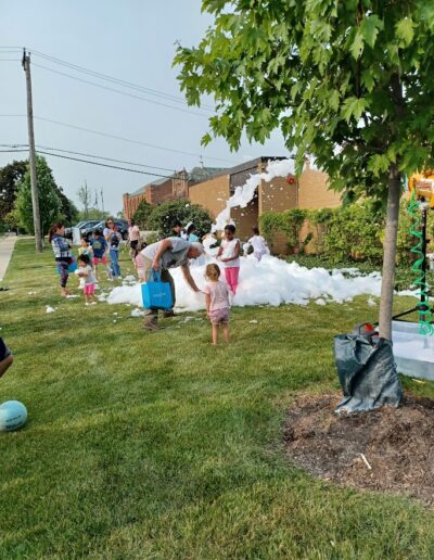 Summer reading 2025 kick-off party kids playing outside the library with foam.