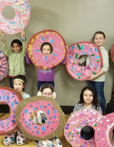 Kids showing their finished work on a giant cardboard donut